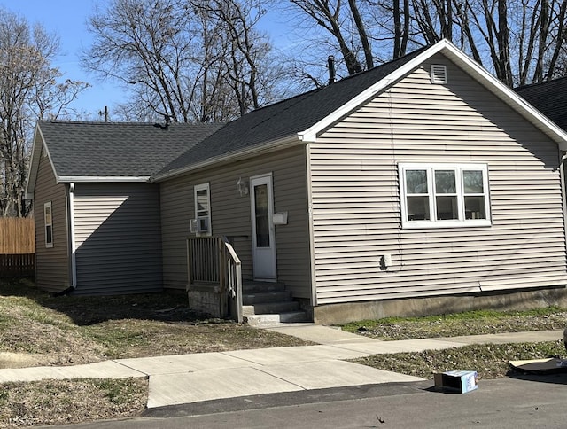 view of front of property featuring a shingled roof and cooling unit