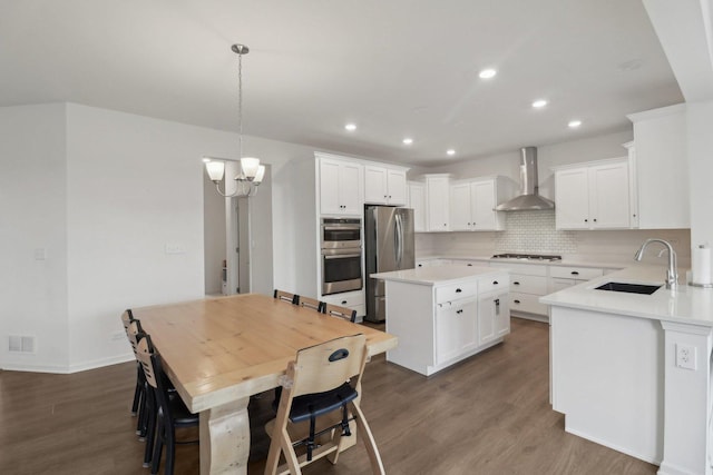 kitchen with a center island, stainless steel appliances, visible vents, a sink, and wall chimney exhaust hood