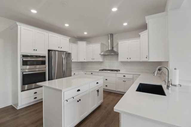 kitchen featuring stainless steel appliances, dark wood-style flooring, a sink, and wall chimney range hood