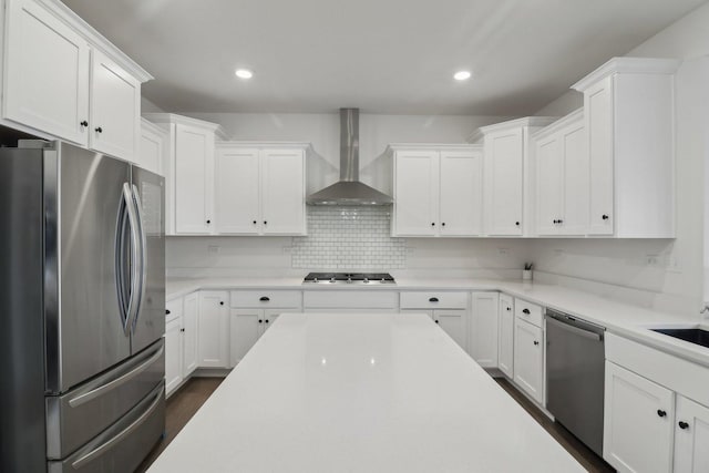 kitchen with wall chimney range hood, white cabinetry, appliances with stainless steel finishes, and light countertops