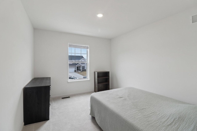 bedroom featuring visible vents, light carpet, and baseboards