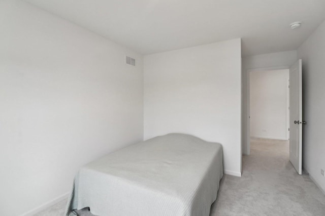 bedroom featuring baseboards, visible vents, and light colored carpet