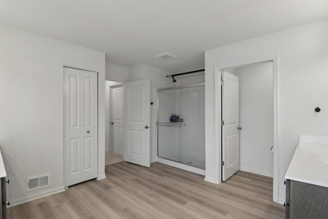 bathroom featuring a stall shower, baseboards, visible vents, wood finished floors, and vanity