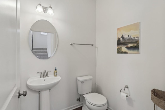 half bath featuring baseboards, a sink, and toilet