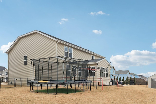 rear view of house with a trampoline and fence