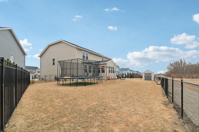 view of yard featuring a fenced backyard, a trampoline, a storage unit, and an outbuilding