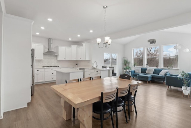 dining space featuring lofted ceiling, light wood-style floors, an inviting chandelier, and recessed lighting