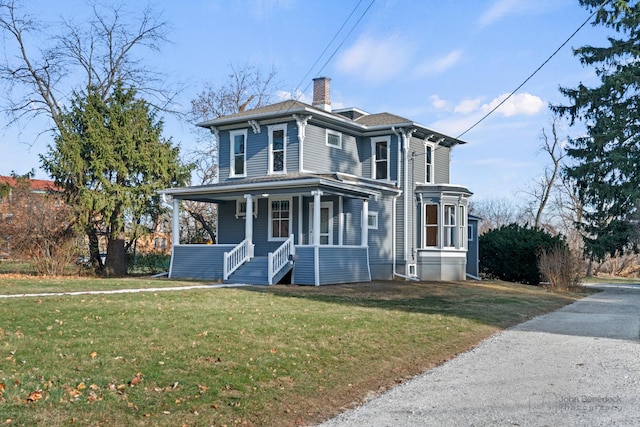 italianate-style house featuring a chimney, a front lawn, and a porch