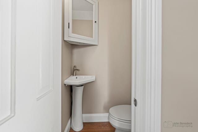 bathroom featuring toilet, baseboards, and wood finished floors