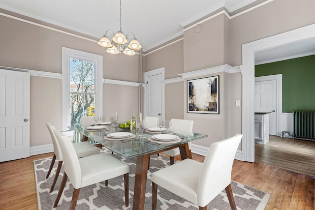 dining area featuring a chandelier, baseboards, light wood-style floors, ornamental molding, and radiator heating unit