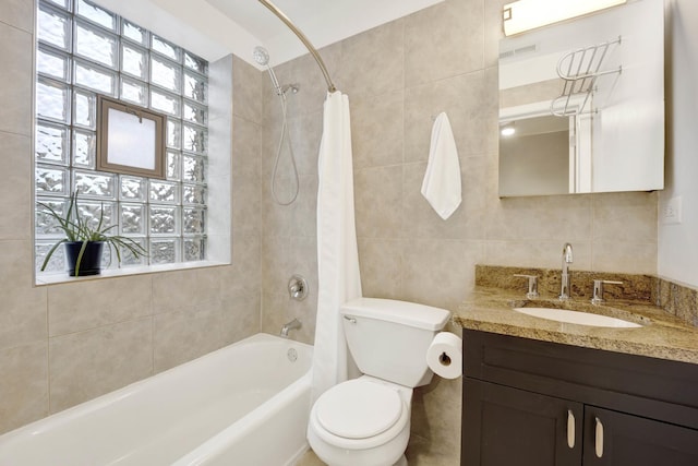 bathroom with a healthy amount of sunlight, tile walls, vanity, and shower / bath combo with shower curtain