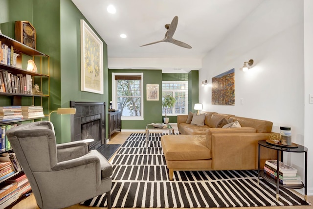 living area with baseboards, a ceiling fan, wood finished floors, a fireplace, and recessed lighting