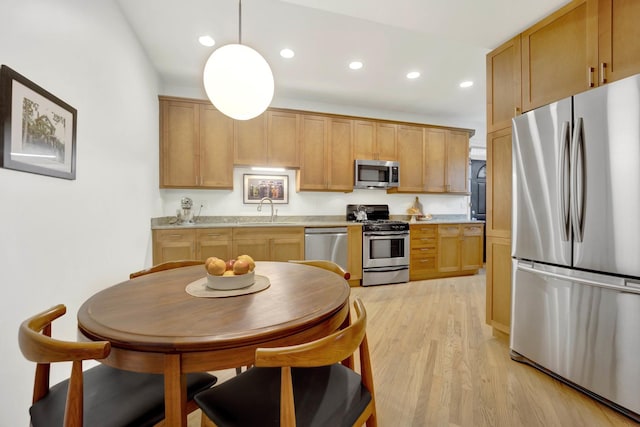 kitchen with stainless steel appliances, light countertops, light wood-type flooring, a sink, and recessed lighting