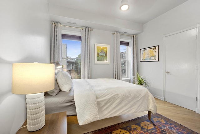 bedroom with light wood-style floors and visible vents