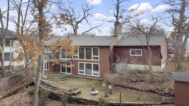 rear view of house featuring a patio area, a shingled roof, and a chimney