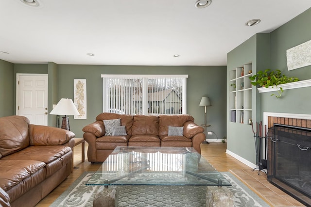 living room featuring recessed lighting, a fireplace, built in features, baseboards, and light wood finished floors