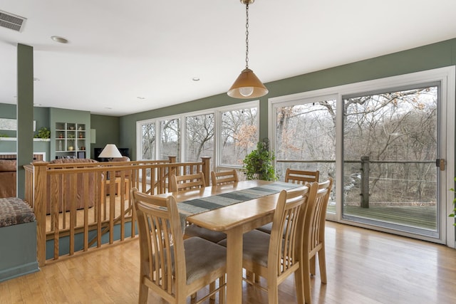 dining area with light wood-style flooring and visible vents