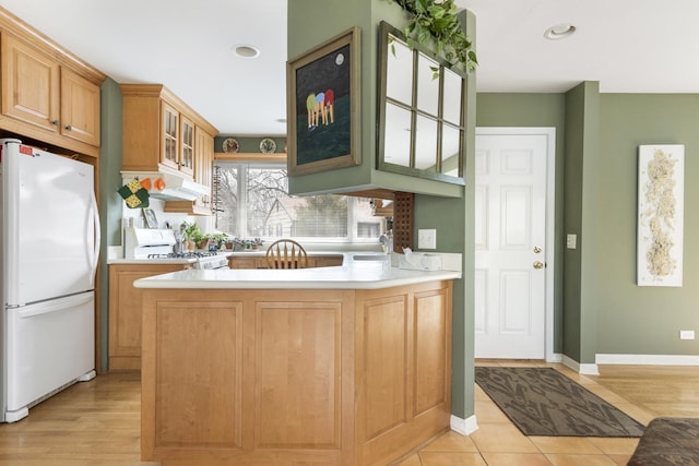 kitchen with recessed lighting, a peninsula, white appliances, light countertops, and glass insert cabinets