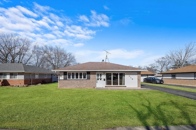 view of front of house featuring driveway, brick siding, and a front yard