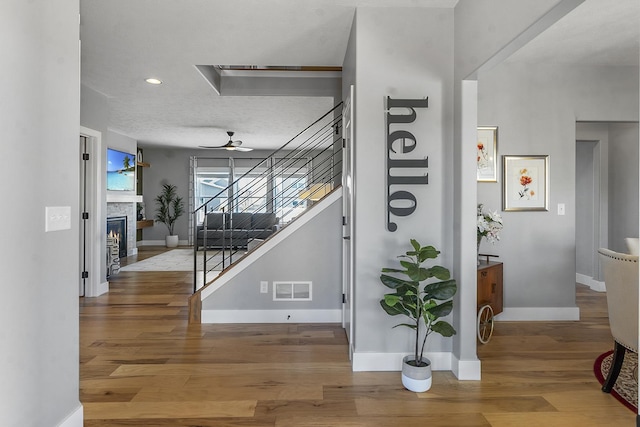 corridor with recessed lighting, wood finished floors, visible vents, baseboards, and stairway