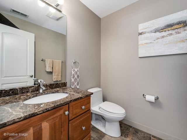 half bathroom featuring baseboards, visible vents, vanity, and toilet