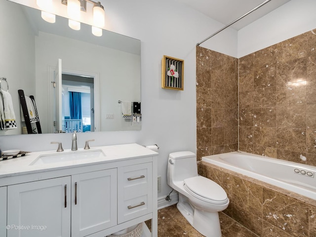 bathroom featuring tiled shower / bath, vanity, and toilet