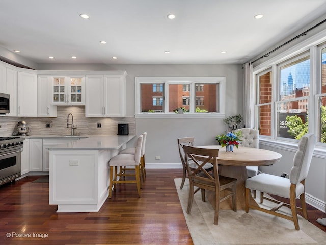 kitchen with backsplash, appliances with stainless steel finishes, glass insert cabinets, white cabinets, and a sink