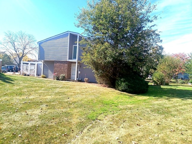 view of home's exterior with brick siding and a lawn