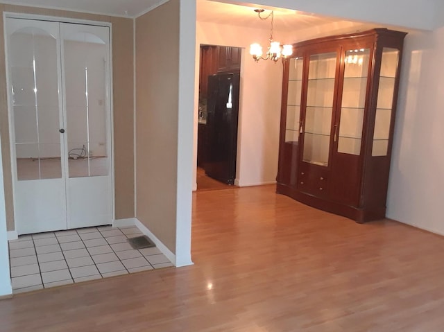 interior space with baseboards, a notable chandelier, and light wood finished floors