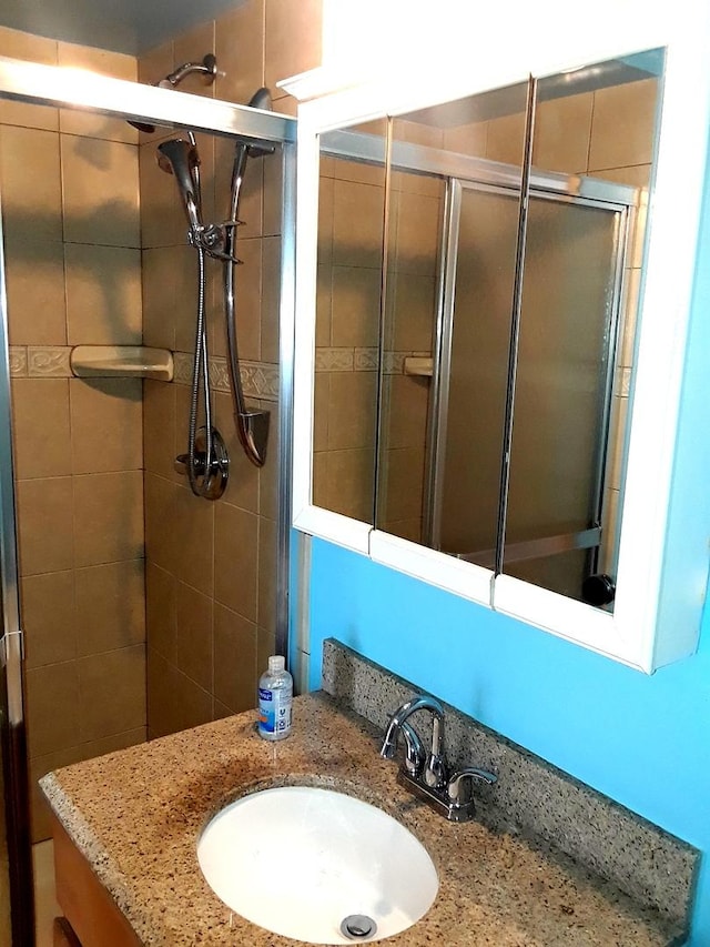 full bathroom with a tile shower and vanity