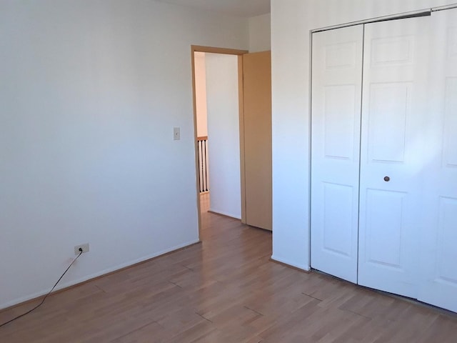 unfurnished bedroom with wood finished floors and a closet
