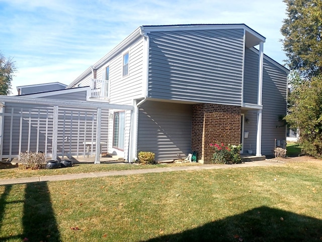 back of house with a balcony, a lawn, and brick siding