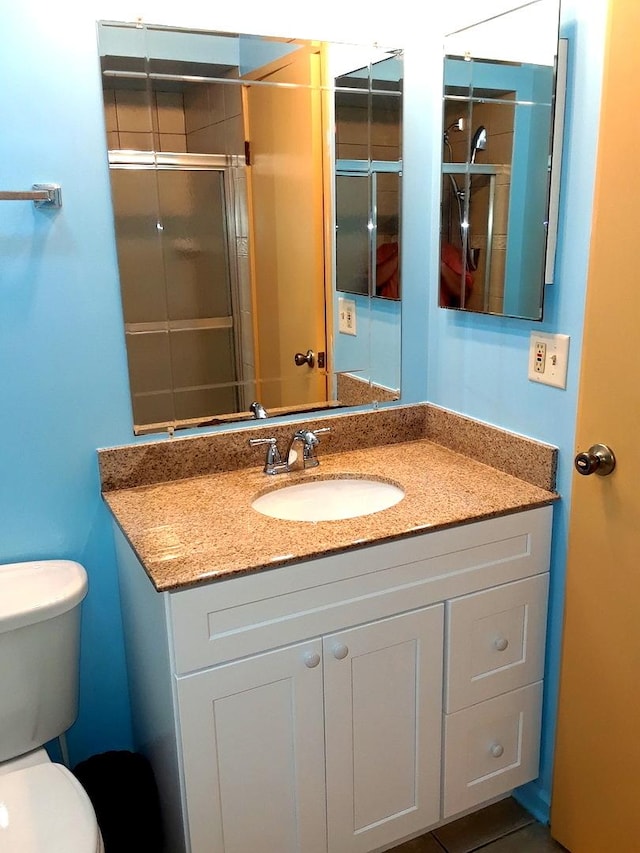 bathroom featuring toilet, a stall shower, and vanity