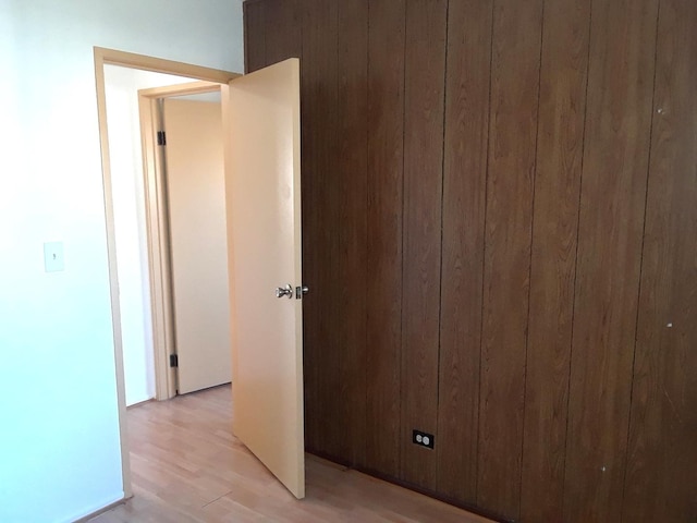 unfurnished room featuring light wood-type flooring and wooden walls