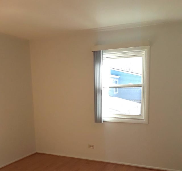 spare room with baseboards and wood finished floors