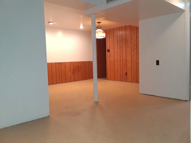 finished basement with a wainscoted wall, wood walls, and visible vents