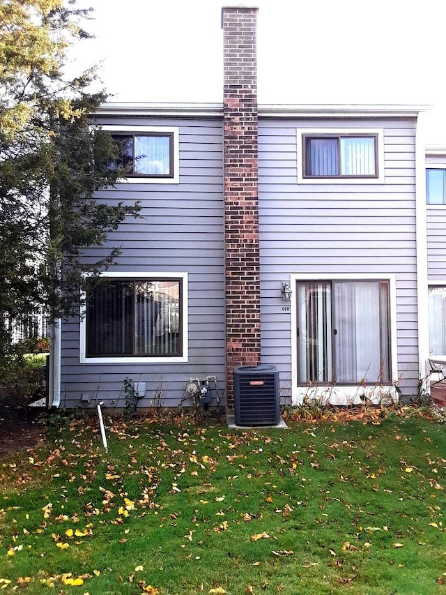 back of house with a yard and central air condition unit