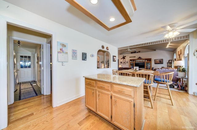 kitchen with open floor plan, light wood-type flooring, a ceiling fan, and a center island