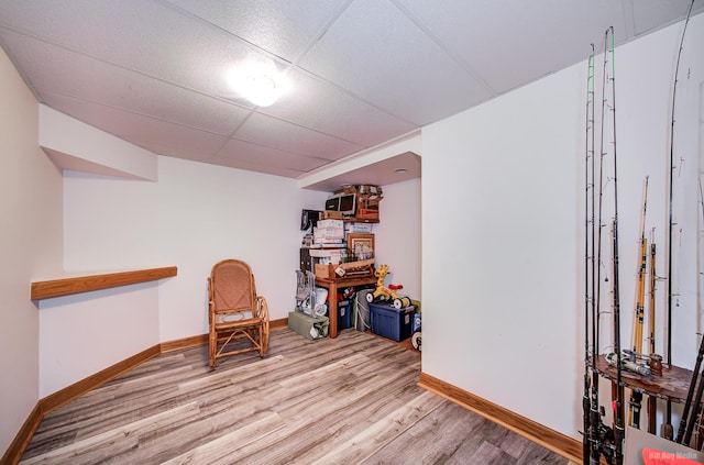 interior space with baseboards, a drop ceiling, and wood finished floors