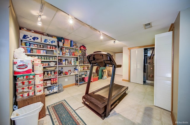 exercise room featuring tile patterned floors, rail lighting, visible vents, and baseboards