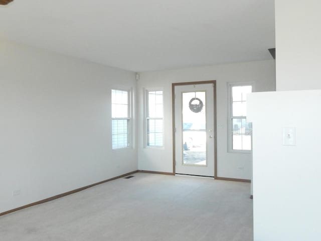 empty room featuring light carpet, visible vents, and baseboards