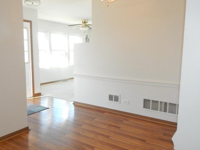 spare room with baseboards, wood finished floors, visible vents, and a ceiling fan