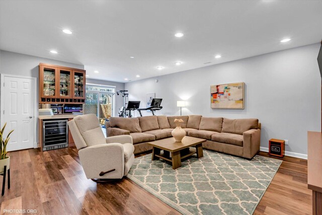 living area with recessed lighting, beverage cooler, wood finished floors, baseboards, and a dry bar