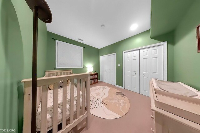 bedroom with multiple closets, a nursery area, visible vents, and baseboards