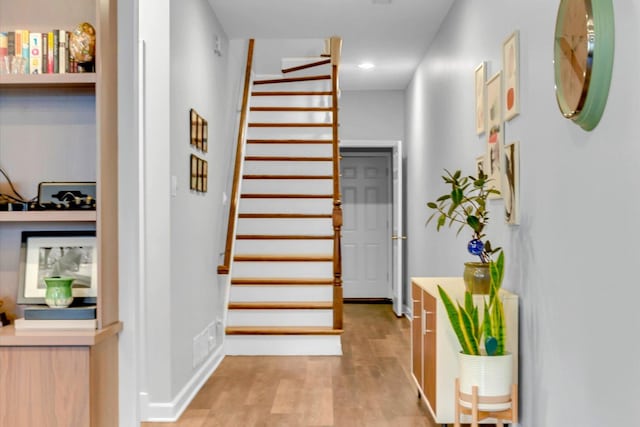 hallway featuring stairs, light wood finished floors, recessed lighting, and baseboards