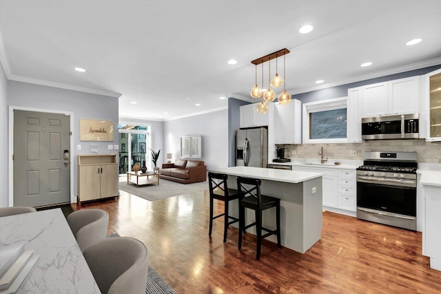 kitchen featuring a breakfast bar, a sink, open floor plan, appliances with stainless steel finishes, and backsplash