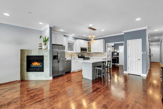 kitchen with a kitchen island, a kitchen breakfast bar, dark wood-type flooring, stainless steel appliances, and light countertops