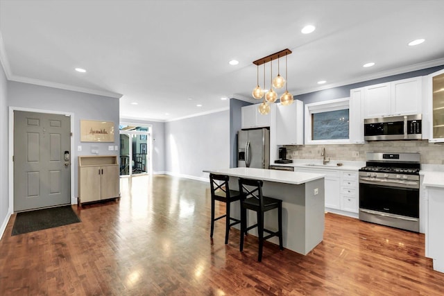 kitchen featuring a center island, stainless steel appliances, decorative backsplash, a sink, and a kitchen bar