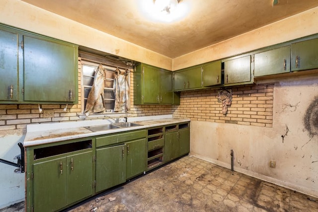 kitchen featuring dark floors, green cabinets, a sink, and light countertops