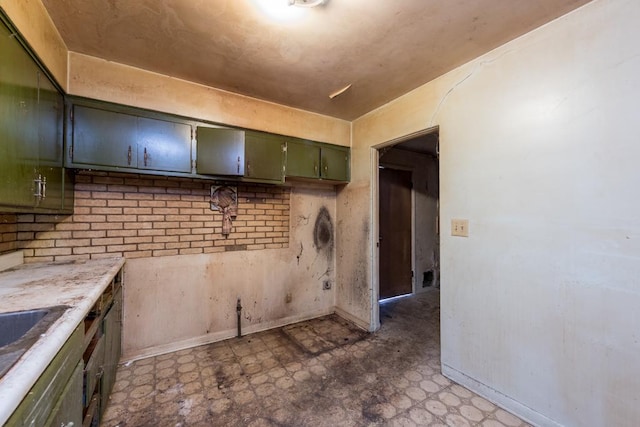 kitchen featuring baseboards, light countertops, green cabinetry, and tile patterned floors